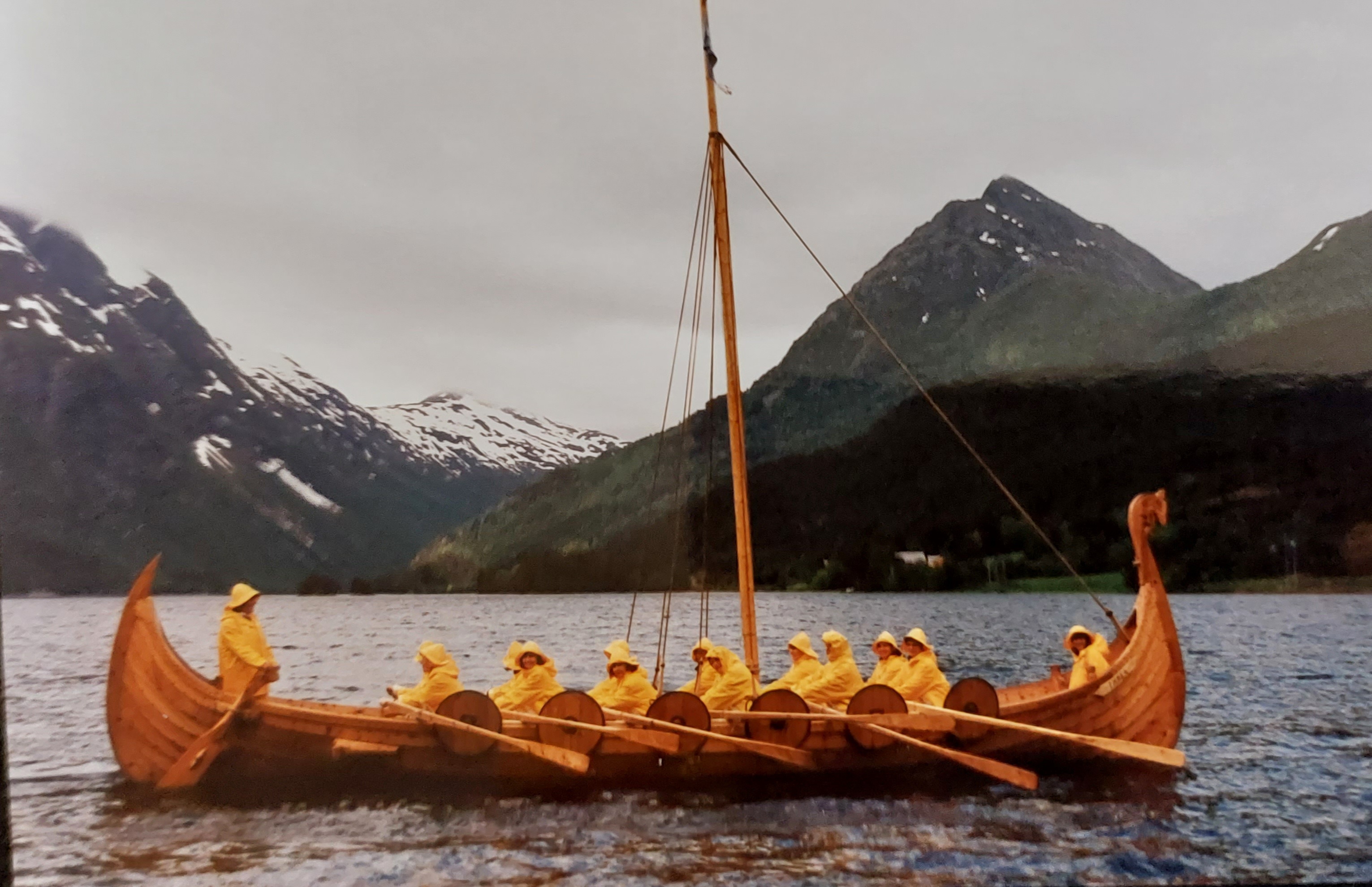Vikingskip med regntøykledde kvinner om bord