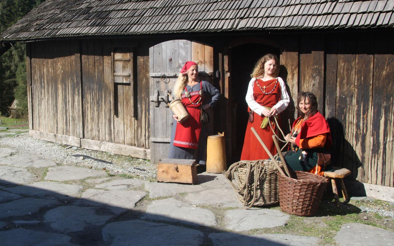 Kvinner i vikingklær utenfor langhus på Avaldsnes 